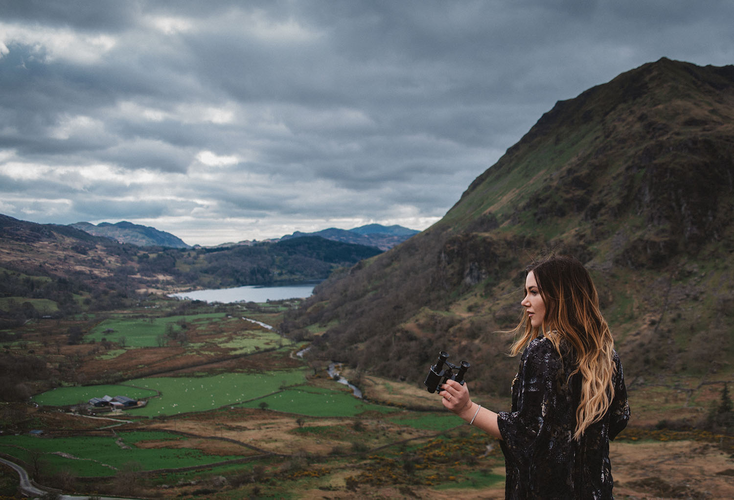 Girl with binoculars standing in front of Nant Gwynant Pass - A King Arthur: Legend of the Sword Filming Location in Wales