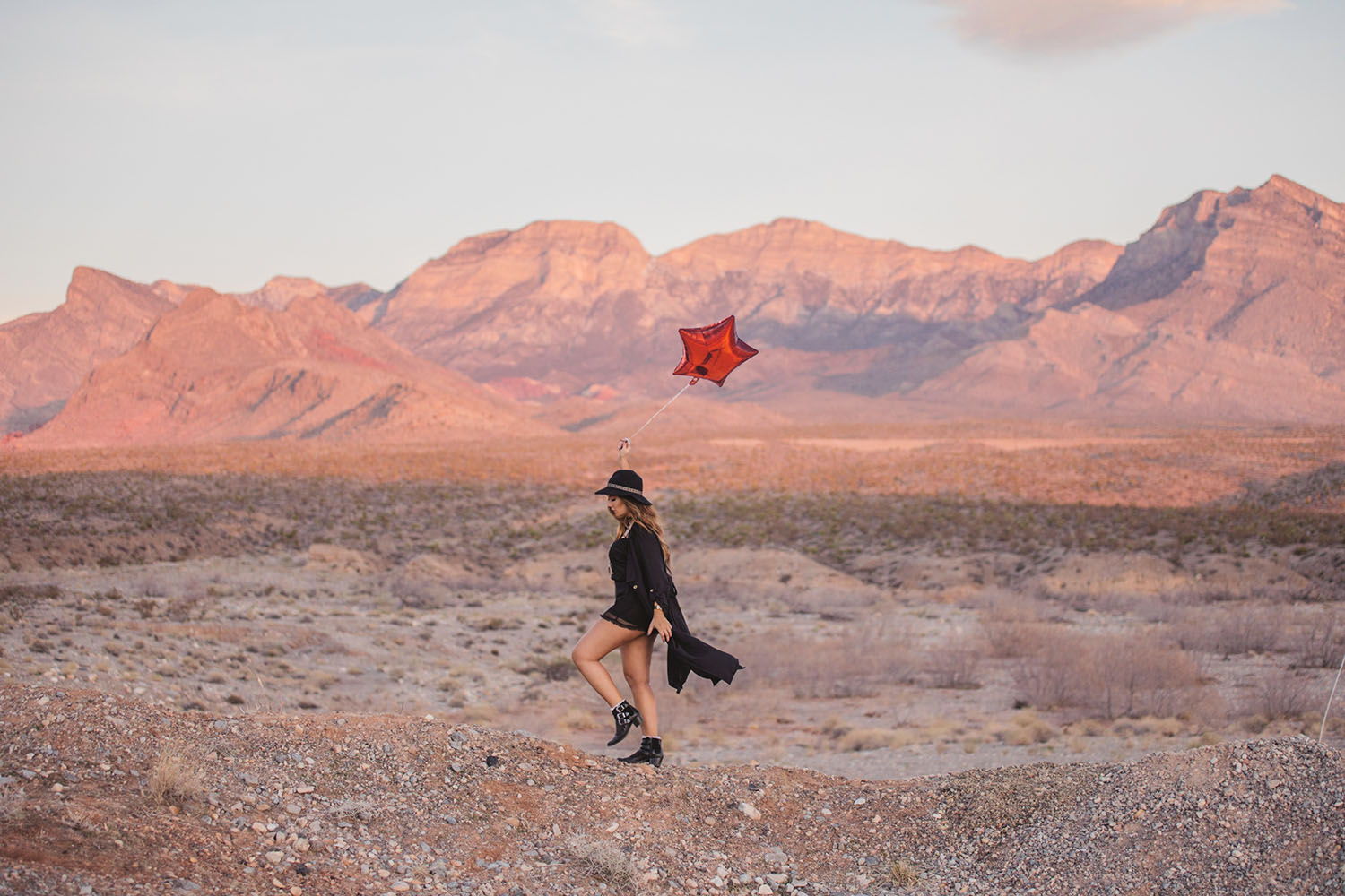 Girl walking with red balloon in sunrise in Red Rock Canyon, Las Vegas