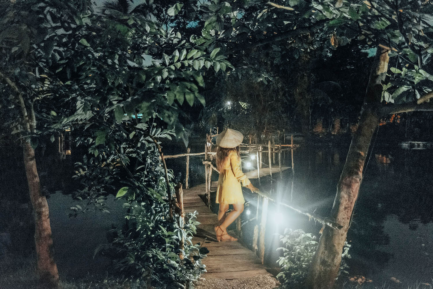 Woman in Yellow Dress with Vietnamese hat standing on bridge in Binh Quoi Village, Ho Chi Minh City, Vietnam