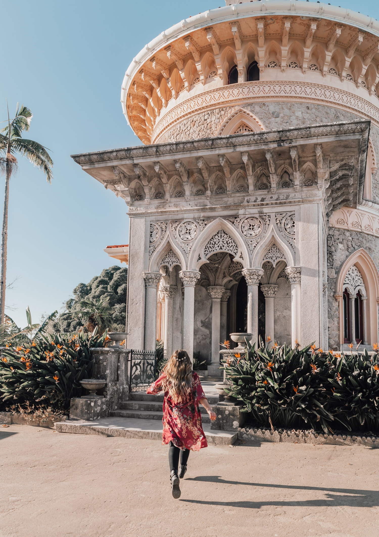 Girl in red kimono and crown running towards Monserrate Palace