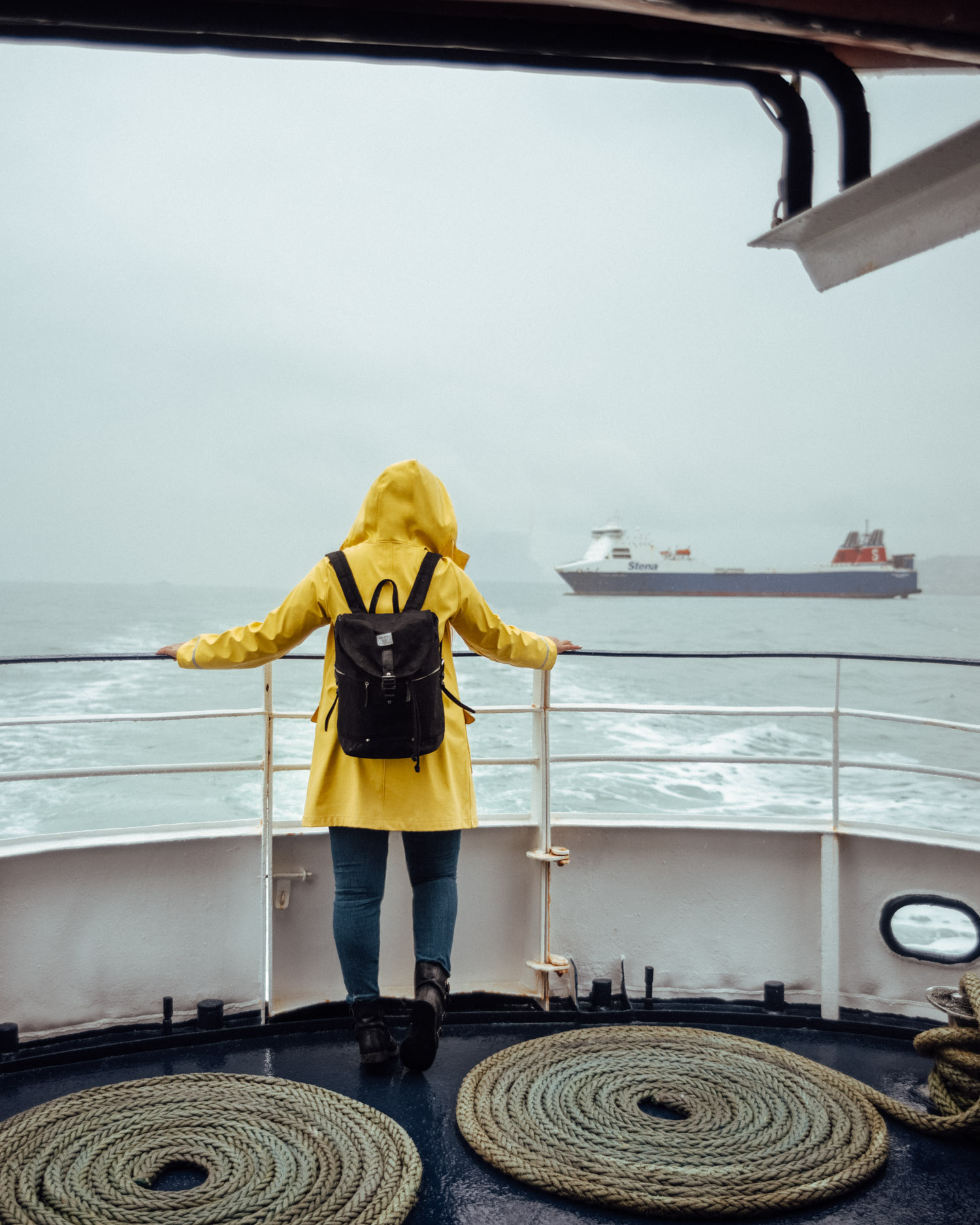 Dublin Bay Cruises to Howth | Woman with yellow raincoat standing on a boat in the rain