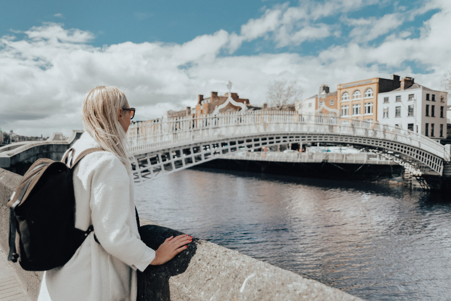 Woman in White Coat & Sandqvist bag standing by Ha’penny Bridge in Dublin