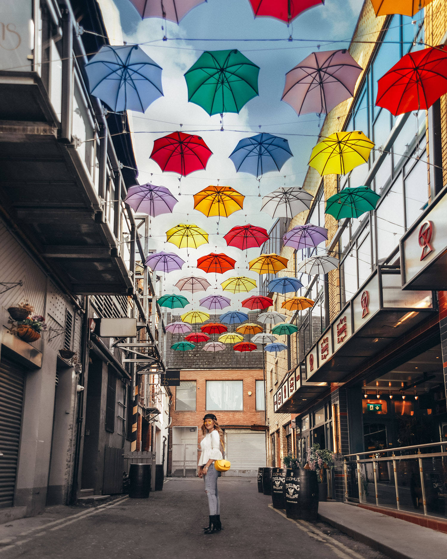 Woman Standing under a colorful roof of umbrellas by Zozimus Bar in Dublin, Ireland