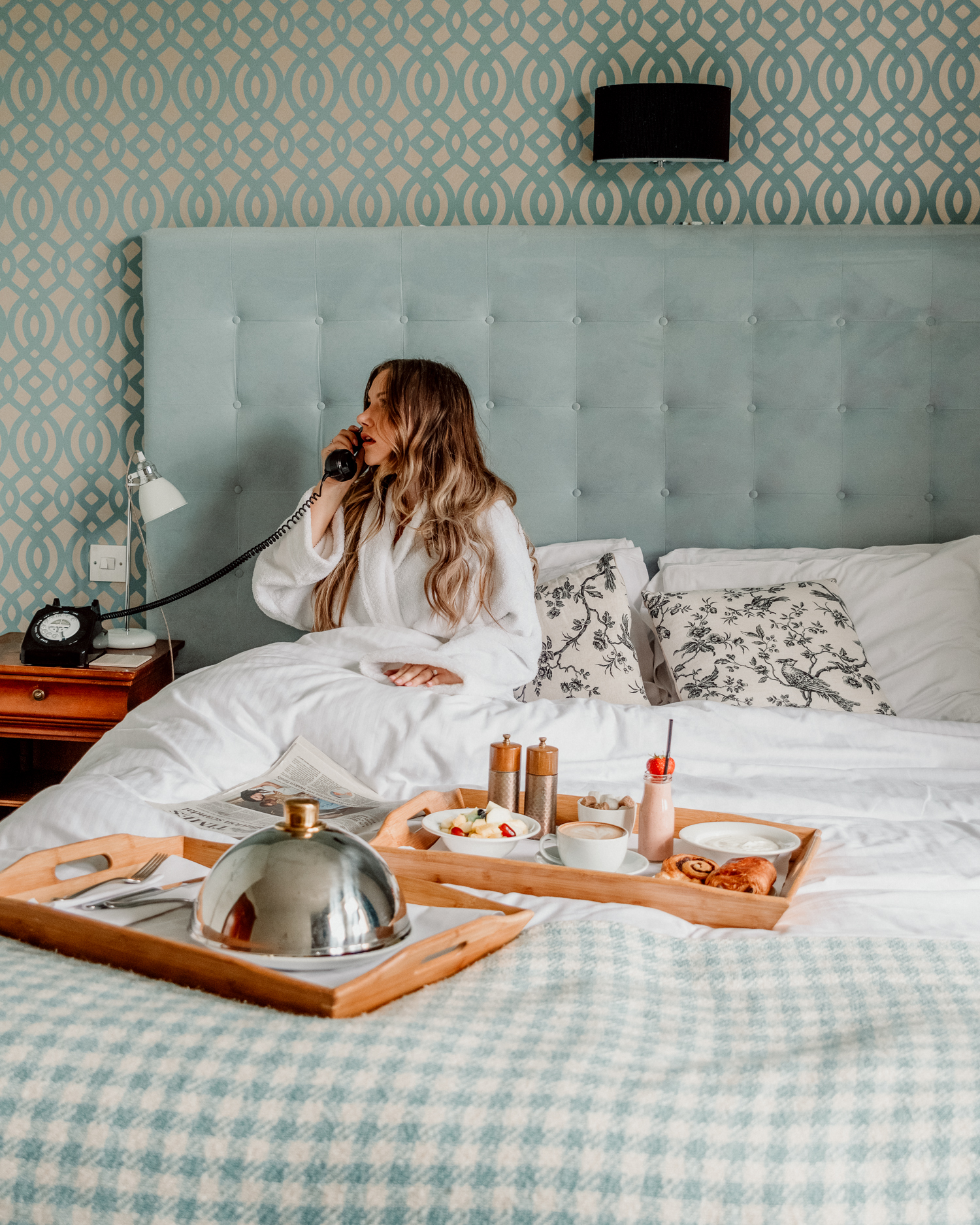 Woman in bath robe talking in telephone in bed at The Alverton Hotel in Cornwall, UK