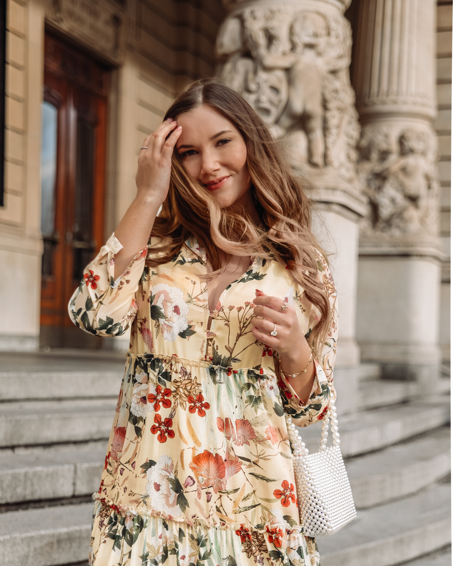 Outfit with yellow floral dress from Ajlajk and pearl bag outside Dramaten in Stockholm, Sweden