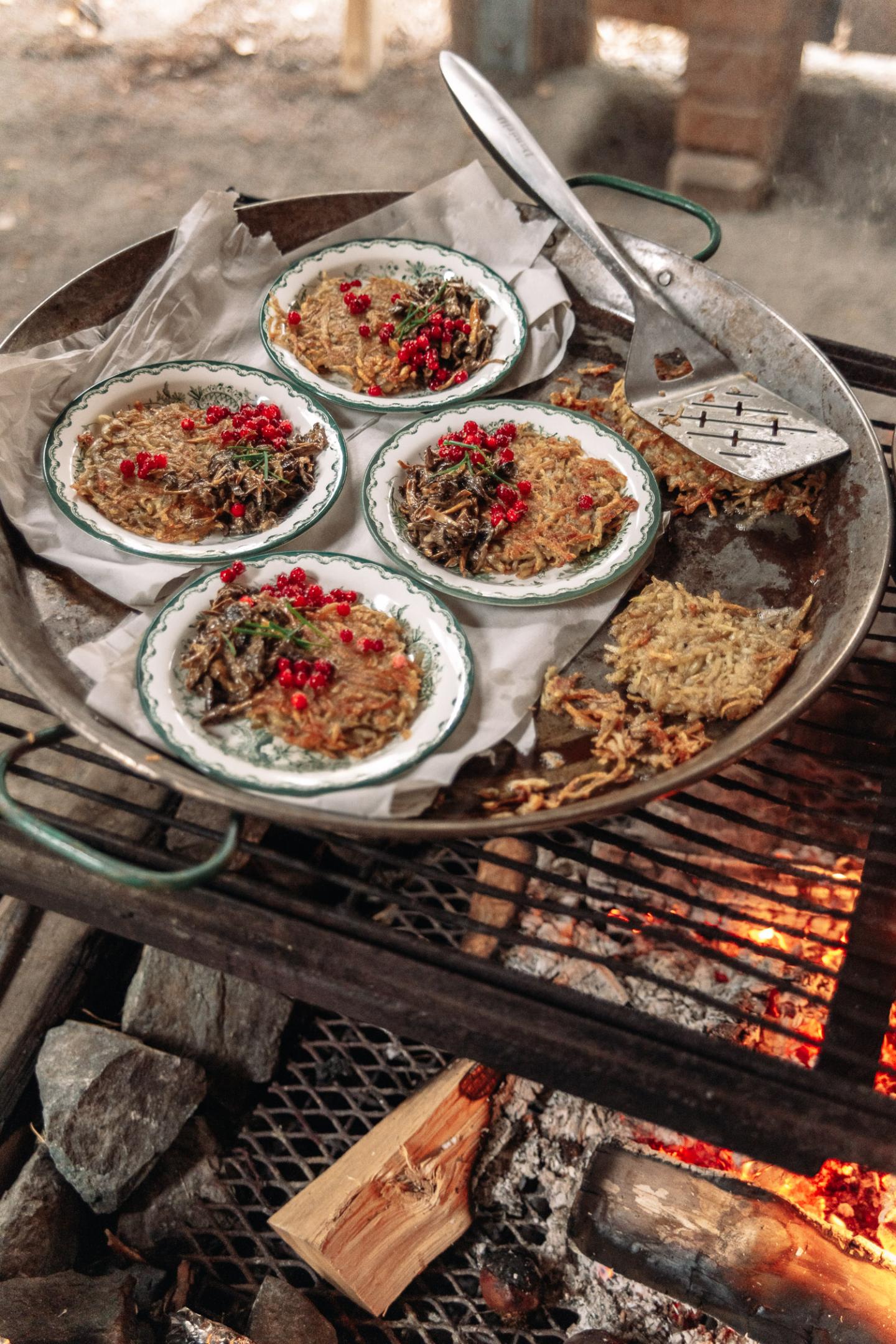 Hash browns, mushrooms and lingonberries are cooked over an open fire in Brevens Bruk, Örebro.