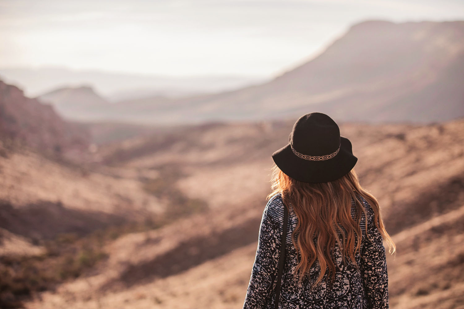 Girl with hair and long hair looking out over the Red Rock Canyon Sunrise