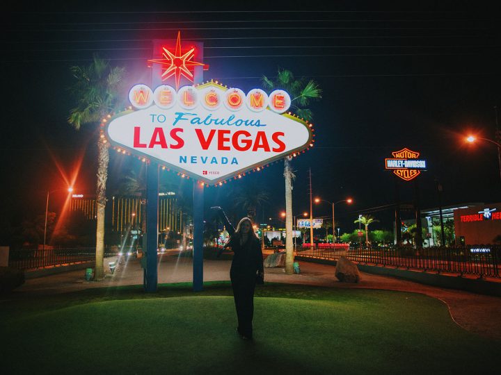 Woman standing in front of Welcome to Fabulous Las Vegas Sign at night